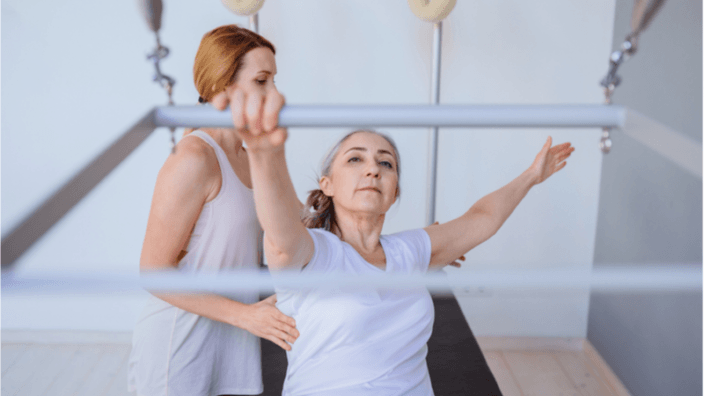 An elderly woman practicing pilates